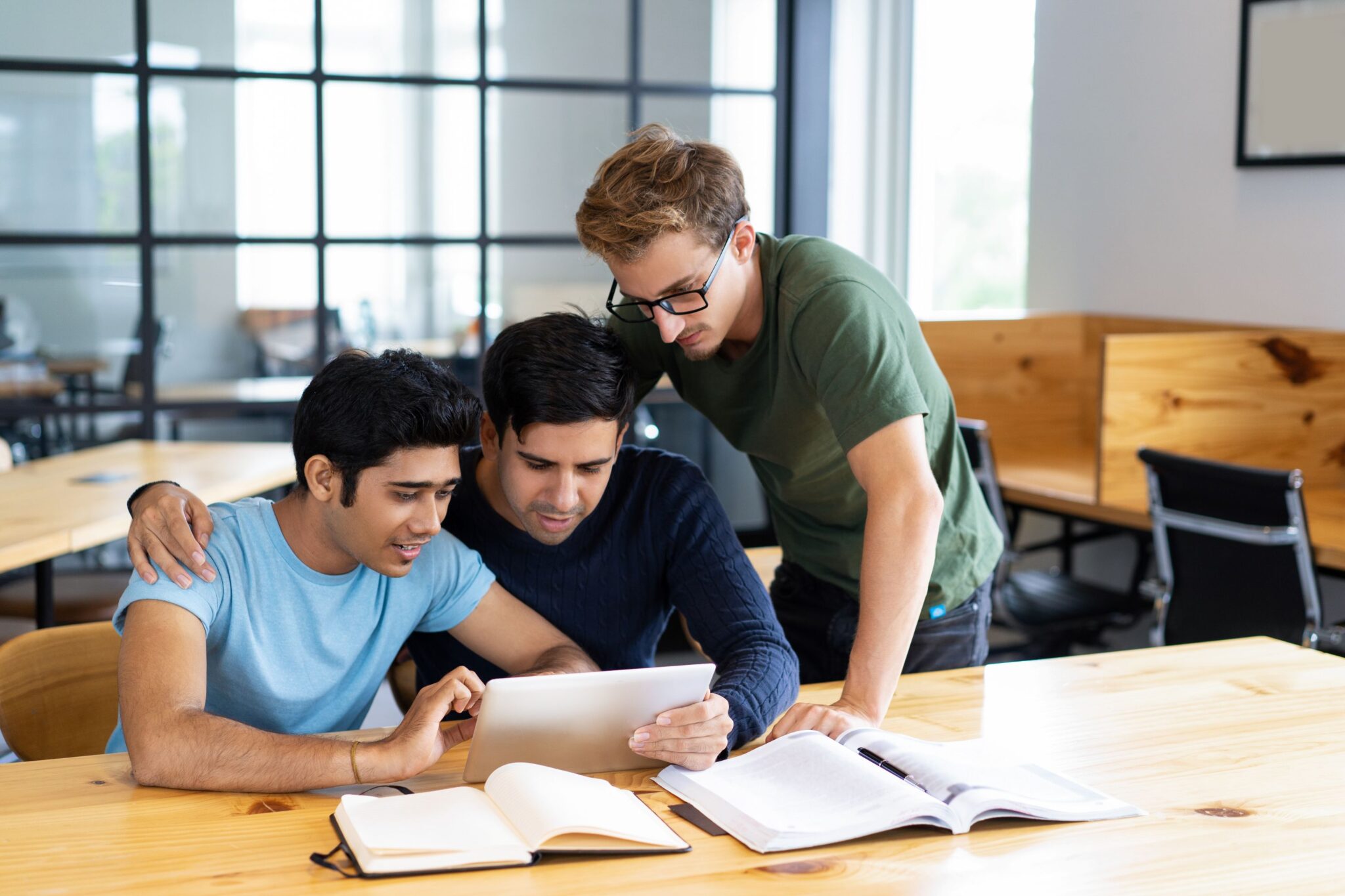 focused-students-browsing-tablet-computer-talking